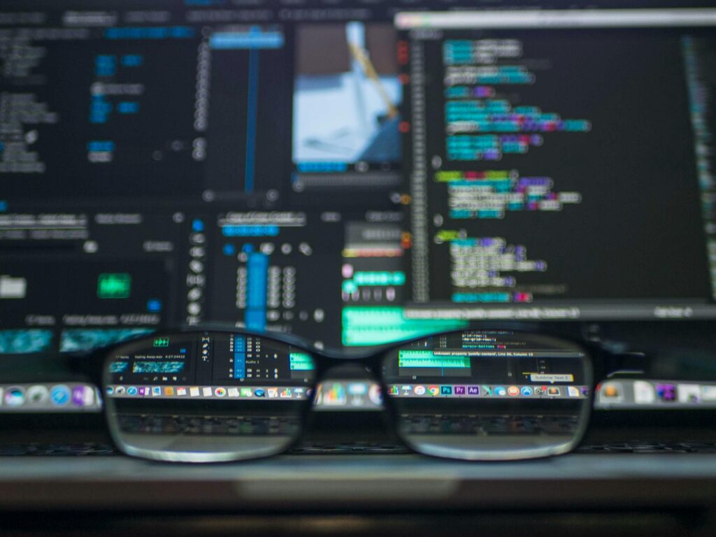 Close-up of glasses focusing on code on a laptop screen — symbolizing clarity in outsourcing cost analysis.